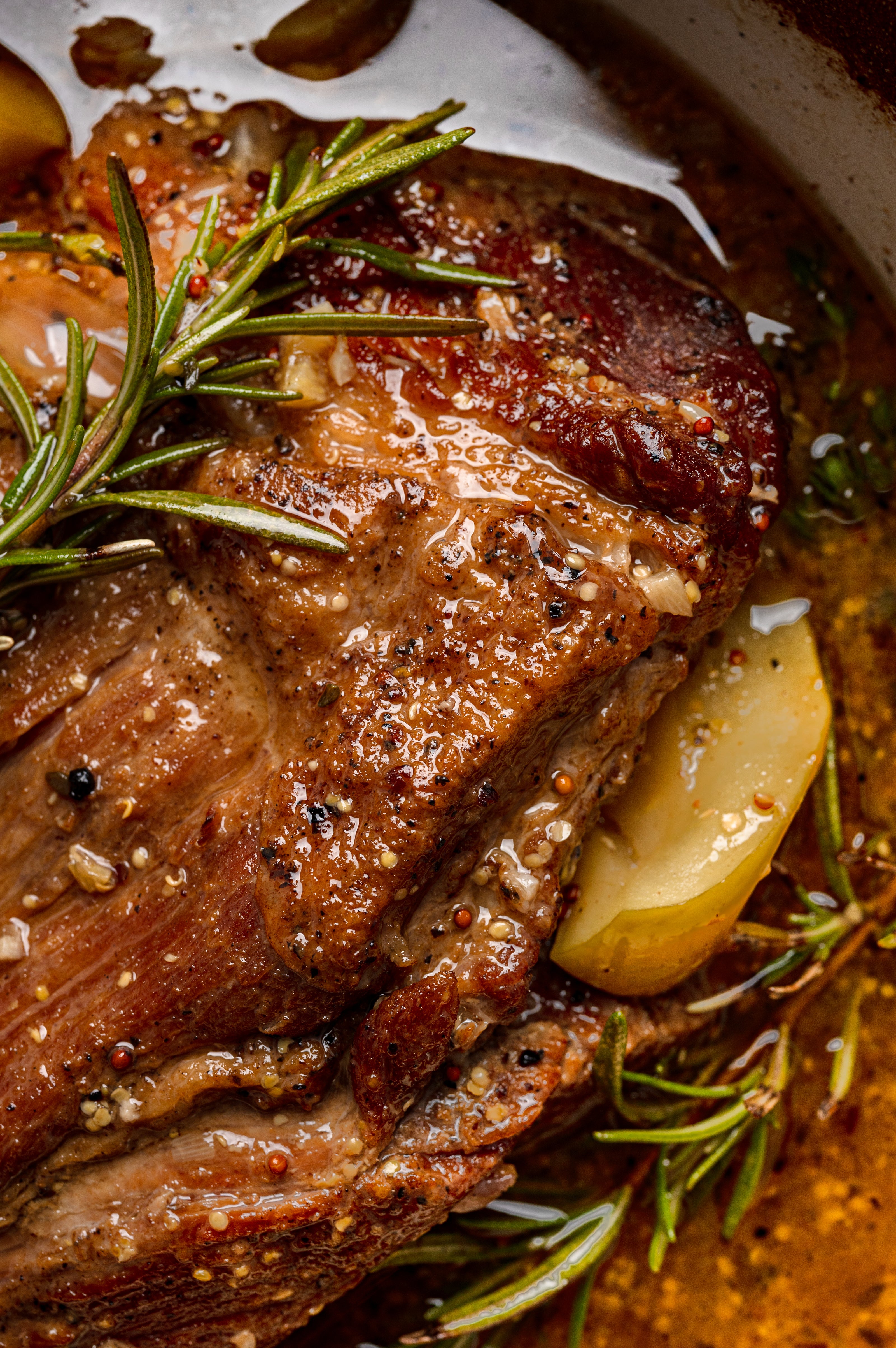 apple cider braised pork shoulder with rosemary and apples in a Dutch oven