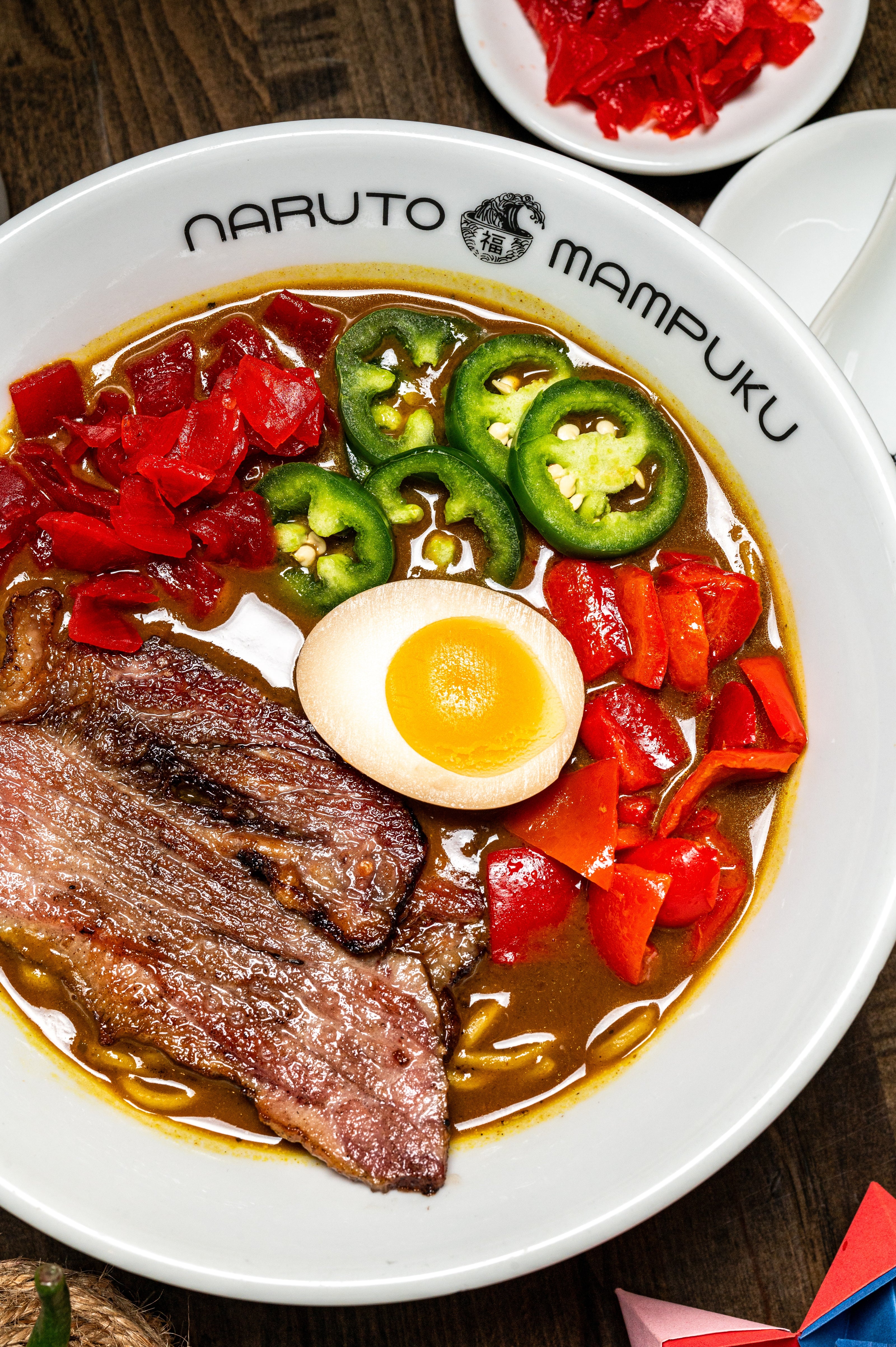 colorful bowl of ramen with char siu, jalapenos, pickled onion, red bell peppers, and a ramen egg