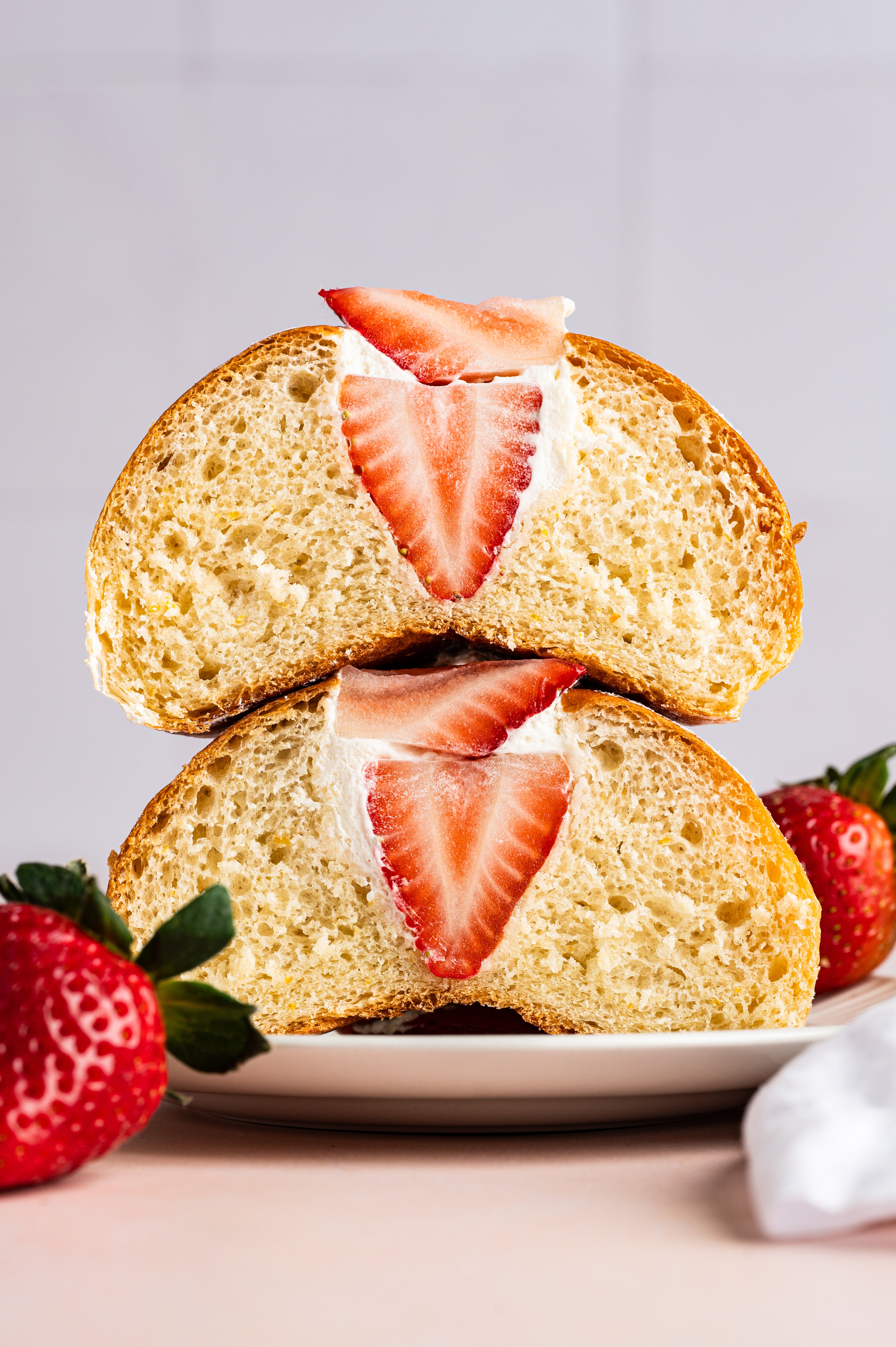 vegan maritozzo cream buns with strawberries sliced in half and stacked on top of each other